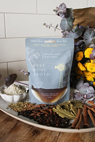 Pouch of organic, grass-fed Australian Beef Bone Broth by Highlands Natural sitting on a plate with various spices and flowers.